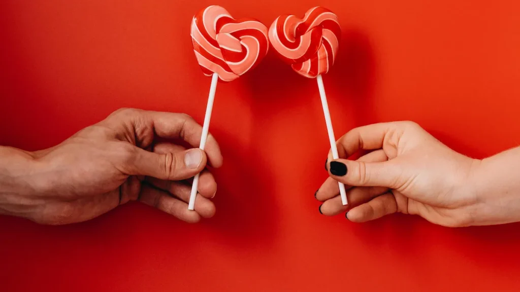 Hands holding heart-shaped lollipops