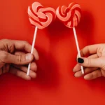 Hands holding heart-shaped lollipops