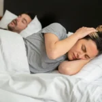 Man snoring and woman closing her ears