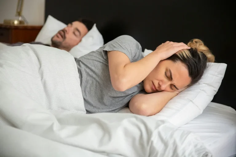 Man snoring and woman closing her ears