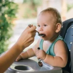 Baby eating food on a chair