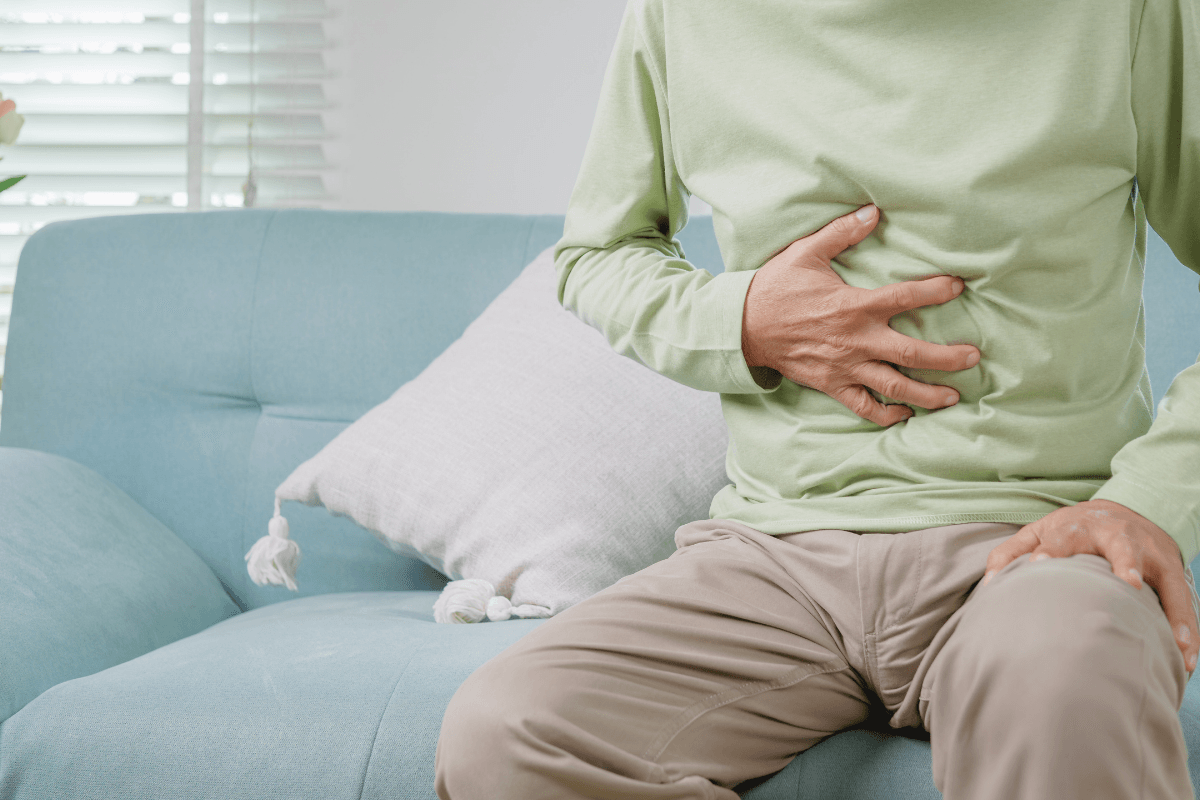 άντρας πιάνει το στομάχι του από πόνο. Καρκίνο του Παγκρέατος